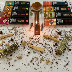 May include: Assortment of incense sticks and smudge sticks with various scents, including white sage, palo santo, sweetgrass, cedar, myrrh, and white copal. The incense sticks are packaged in colorful boxes with the brand name "Tribal Soul" printed on them. The smudge sticks are bundled with twine and are ready to be burned.