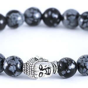 May include: A black and gray snowflake obsidian beaded bracelet with a silver Buddha charm.