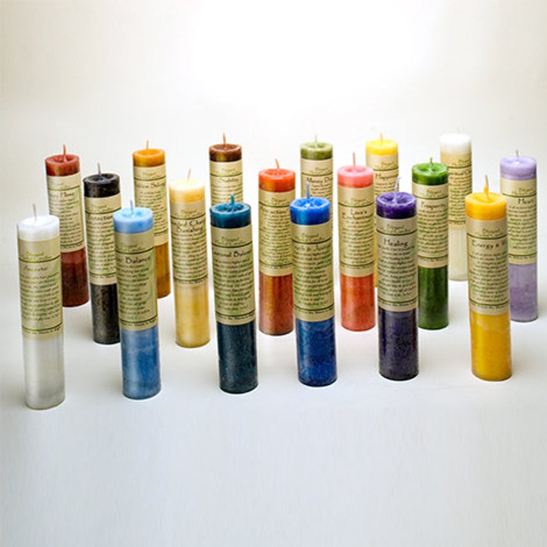 May include: A collection of cylindrical candles in various colors, including white, blue, green, and yellow. Each candle has a label wrapped around it. The candles are arranged on a white surface.