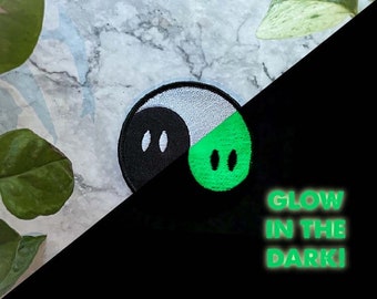 May include: A black and white yin yang symbol with a green glow-in-the-dark half. The text "GLOW IN THE DARK!" is written below the symbol.