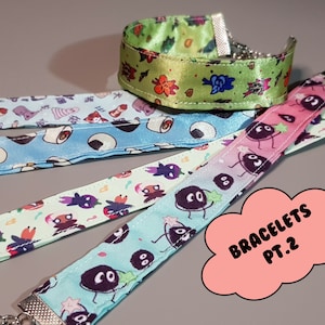 Pode incluir: Cinco pulseiras de tecido coloridas com padrões diferentes. As pulseiras apresentam personagens de desenhos animados e designs. As pulseiras são etiquetadas como "Bracelets Pt. 2".
