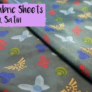 Könnte beinhalten: A4 Stoffblätter aus Leinen und Satin mit einem blauen, grünen, roten und goldenen Druck verschiedener Symbole. Der Stoff ist dunkelgrau.