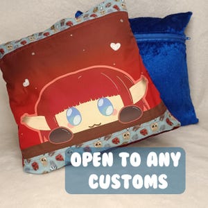 May include: Two decorative cushions. One cushion features a cartoon character with red hair and blue eyes on a red background. The other cushion is a solid blue. The text "OPEN TO ANY CUSTOMS" is displayed on a blue rectangle.