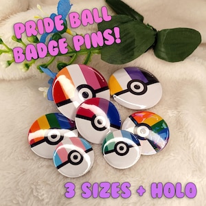 Op de afbeelding: Een verzameling Pride Ball-speldjes in verschillende kleuren, waaronder regenboog, roze en blauw, met een wit en zwart ontwerp. De ronde speldjes bevatten de tekst "PRIDE BALL BADGE PINS!" en "3 SIZES + HOLO".