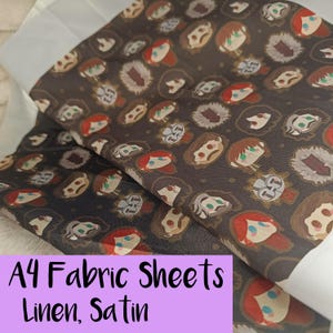 May include: A4 fabric sheets in linen and satin. The fabric has a dark brown background with a repeating pattern of cartoon faces with red hair and other characters. The text "A4 Fabric Sheets Linen, Satin" is in a purple box.