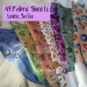 May include: A collection of A4 fabric sheets in linen and satin, featuring various colourful cartoon character patterns. The prints include blue, green, orange, white, purple, and tan backgrounds with repeating faces of animated creatures.