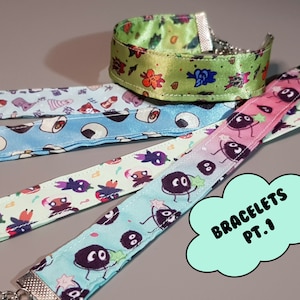 May include: Four fabric bracelets with various patterns and silver chain clasps. The bracelets feature designs of sushi, cartoon characters, and other colorful illustrations. One bracelet is green with floral designs. The text "BRACELETS PT.1" is in a speech bubble.