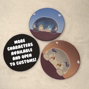 May include: Three round coasters with different designs. One coaster is black with white text that reads "More Characters Available and Open to Customs!" The other two coasters feature cartoon characters peeking over the edge of a surface. One character has blue hair and yellow eyes, and the other has grey hair and brown eyes.