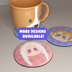 May include: Three round coasters featuring different cartoon character designs. The coasters are made from a soft, absorbent material. The text "MORE DESIGNS AVAILABLE!" is printed on a purple background.