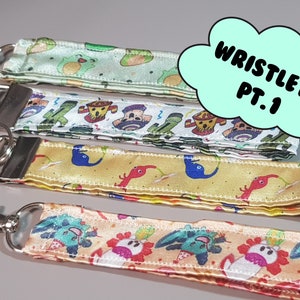 May include: Four colorful wristlets with keychains. Each wristlet features a different cartoon design. The wristlets are labeled "Wristlets Pt. 1".