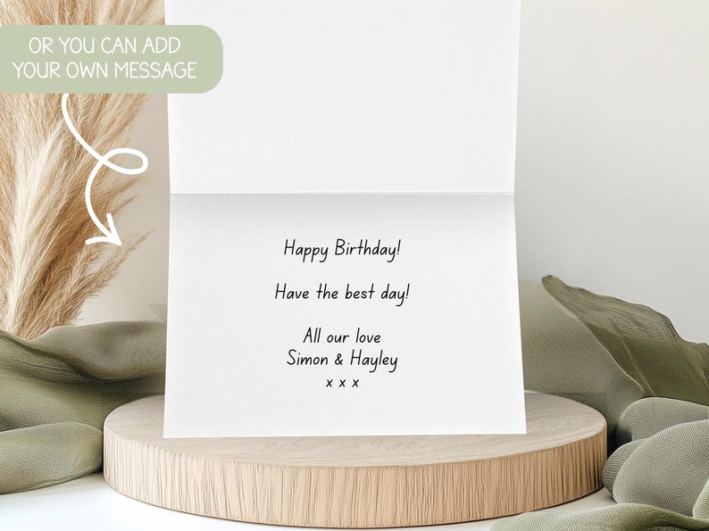 May include: A white greeting card with the message "Happy Birthday!" and a personal note. The card is open, revealing the message inside. The card is on a wooden stand with decorative elements.