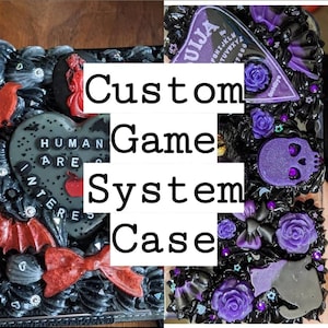 May include: Custom game system case with a gothic theme. The case is black with red and purple accents, including a heart, bats, bows, roses, and a Ouija board. The text "HUMAN ARE INTERESTED" is on the heart.