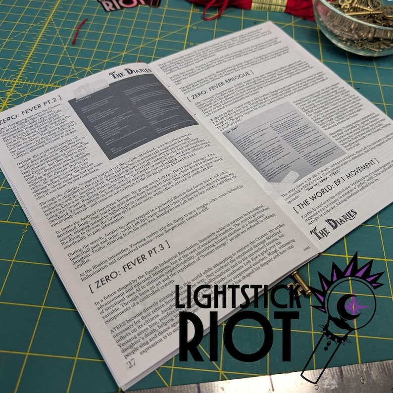 Puede incluir: Libro abierto con texto, titulado "The Diaries", sobre una esterilla de corte verde. Las p&aacute;ginas muestran texto detallado y un gr&aacute;fico. El logotipo "LIGHTSTICK RIOT" es visible en la parte inferior derecha, con una peque&ntilde;a ilustraci&oacute;n.