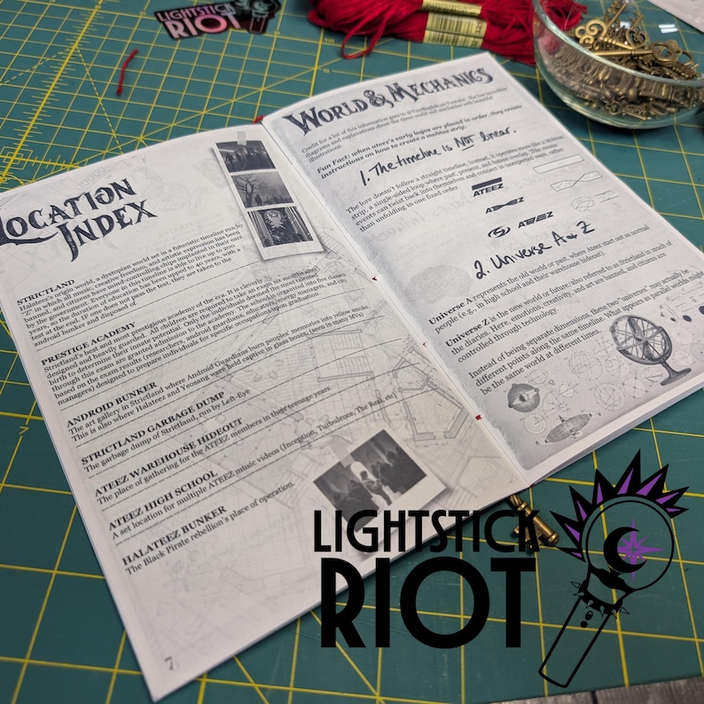Puede incluir: Libro abierto con los t&iacute;tulos "World & Mechanics" y "Location Index". Las p&aacute;ginas presentan texto e ilustraciones. El libro est&aacute; sobre una esterilla de corte verde, con hilo rojo y una pegatina "Lightstick Riot".
