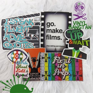 May include: A collection of colorful vinyl stickers with film-related themes. Stickers include text like "I Speak Fluent Movie Quotes," "go. make. films," and "Hurry Up & Wait." Other stickers feature a film camera, an eye, and a color test pattern.