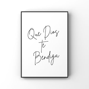 May include: A framed print with the words "Que Dios te Bendiga" in elegant black script on a white background. The artwork is enclosed in a black frame, suitable for home decor or as a gift.