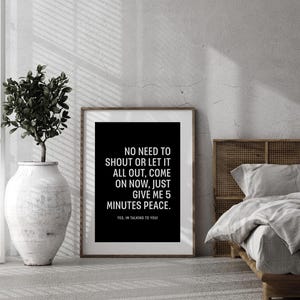 May include: A framed black and white print with the text "NO NEED TO SHOUT OR LET IT ALL OUT, COME ON NOW, JUST GIVE ME 5 MINUTES PEACE." The print is in a bedroom setting with a bed and a decorative plant.