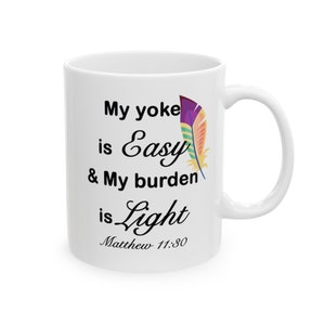 May include: White ceramic mug with a black and white quote that reads "My yoke is easy & My burden is light Matthew 11:30". A colorful feather is depicted next to the quote.