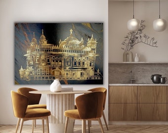 May include: A gold-toned illustration of a Sikh temple, with intricate details, set against a dark blue and gold marbled background. The image is framed and hanging on a white wall in a modern living room.