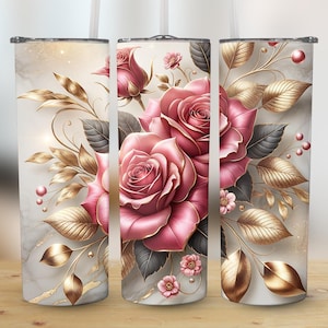 Op de afbeelding: Drie roestvrijstalen bekers met een bloemenontwerp. Het ontwerp toont grote roze rozen, gouden bladeren en kleine roze bloemen tegen een marmerachtige achtergrond. De bekers hebben een rietje en een zilveren deksel.