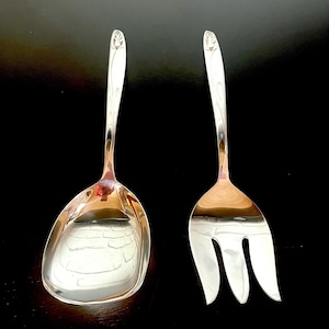 May include: A silver salad serving set with a spoon and fork. The handles are decorated with a floral design.