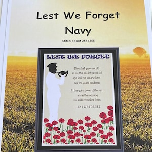 May include: A framed cross-stitch design featuring a black silhouette of a soldier playing a trumpet. The design includes red poppies and the text "Lest We Forget" in a white font. The text below the soldier reads "They shall grow not old as we that are left grow old age shall not weary them nor the years condemn At the going down of the sun and in the morning we will remember them Lest We Forget".