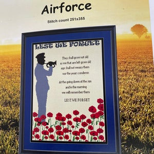 May include: Framed cross-stitch artwork with the text "Lest We Forget Airforce." The design features a silhouette of a soldier playing a bugle, a field of red poppies, and a poem. The artwork is framed in a black frame with a blue mount.