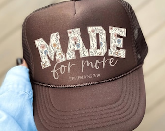 May include: Brown trucker hat with a floral design and the text "MADE for more EPHESIANS 2:10"
