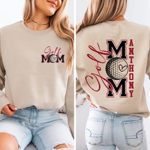 May include: Beige sweatshirt with the text "Golf Mom" and a golf ball graphic on the front. The back features the text "Golf Mom" in a cursive font, along with the name "Anthony" and a golf ball graphic.