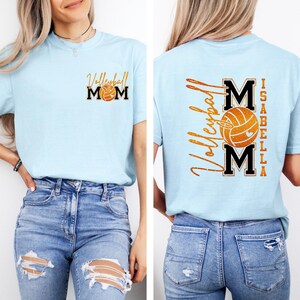 May include: Light blue t-shirt with "Volleyball Mom" and a volleyball graphic on the front. The back of the shirt features "Volleyball" and "MOM" with a volleyball graphic, and the name "Isabella".