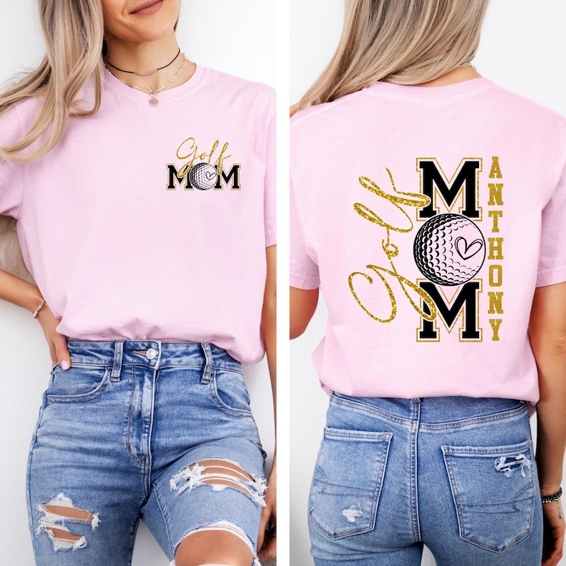 May include: A light pink t-shirt with a golf-themed design. The front features "Golf Mom" in gold script and black block letters, with a golf ball graphic. The back displays "Love Mom" in gold script, with "MOM" in black block letters and a golf ball graphic.