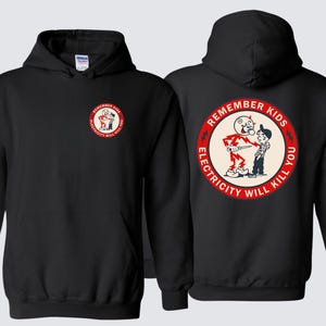 Peut inclure: Un sweat-shirt à capuche noir avec un petit motif circulaire sur la poitrine gauche et une version plus grande au dos. Le motif représente un personnage de dessin animé fait d'éclairs pointant vers un enfant avec le texte REMEMBER KIDS ELECTRICITY WILL KILL YOU.