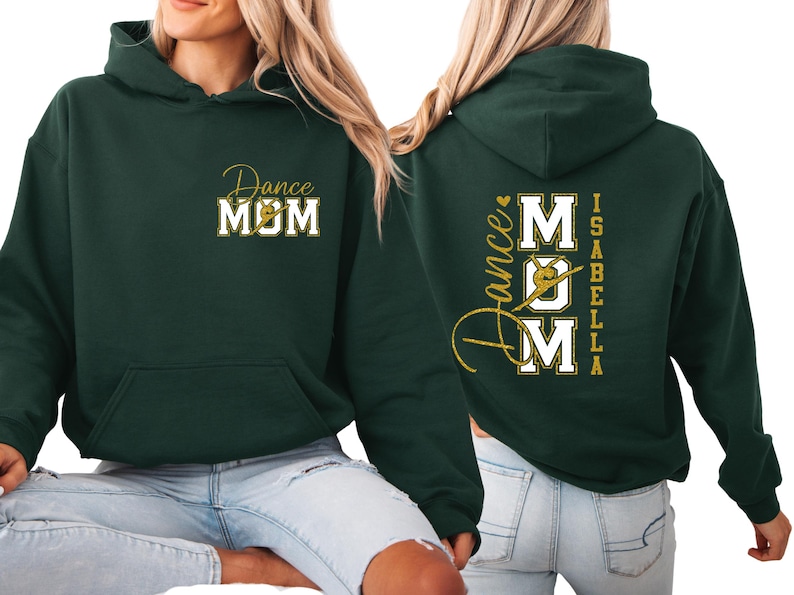 May include: A dark green hoodie with the words "Dance MOM" in gold script and white block letters on the front. The back of the hoodie features the words "Dance MOM" with a dancer graphic and the name "Isabella" in gold.