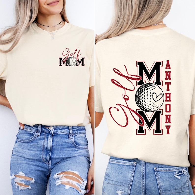 May include: Cream-colored t-shirt with "Golf Mom" and a golf ball graphic on the front. The back features "Golf Mom" in script and the name "Anthony" in a vertical block, also with a golf ball graphic.
