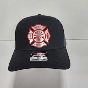 May include: Black trucker hat with a silver and red firefighter emblem on the front. The emblem has the text "LINE 1 TEXT" and "LINE 2 TEXT". The hat has a curved brim and a mesh back. The hat is adjustable.