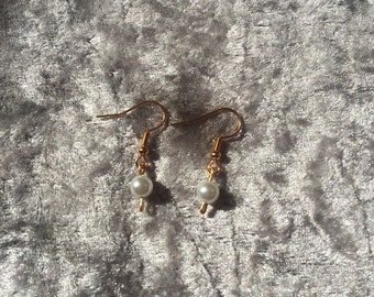 Gold dangling simple pearl earrings.