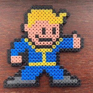 May include: A pixel art character made of colorful beads. The character is wearing a blue jumpsuit with yellow accents and has a yellow head with a black outline. The character is giving a thumbs up.