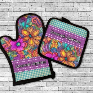 May include: A set of two purple and teal oven mitts with a floral pattern and the text "Homemade Happiness".