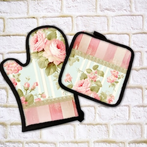 May include: Oven mitt and pot holder set. The set features a floral design with pink roses and green leaves on a light blue and pink striped background. The edges are trimmed with black fabric.