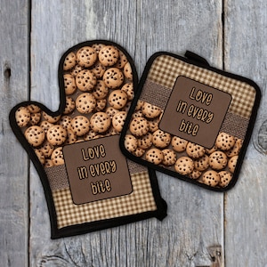 May include: A set of two brown and white oven mitts with a chocolate chip cookie pattern and the text "Love in every bite".