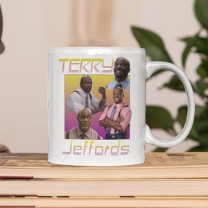 以下が含まれることがあります： 4人の男性と「TERRY JEFFORDS」というテキストが描かれたカラフルなグラフィックが施された白いセラミックマグカップです。
