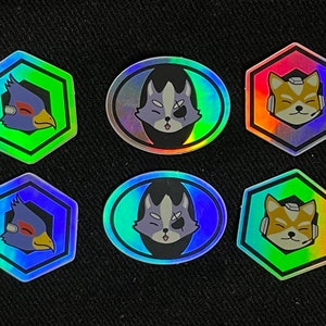 May include: Six holographic stickers featuring characters from the video game Star Fox. The stickers are in various shapes, including hexagons and ovals. The characters include Fox McCloud, Falco Lombardi, and Peppy Hare.