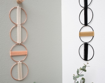 May include: Two wall hangings made of yarn and wire. The left wall hanging has four circles, two are beige, one is peach, and one is white. The right wall hanging has four circles, two are black, one is gold, and one is white.