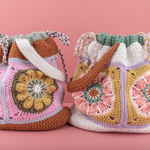 Puede incluir: Dos bolsas de crochet con coloridos patrones florales. Las bolsas están hechas con hilo de diferentes colores y tienen un cierre de cordón.