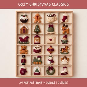 Può includere: Un espositore in legno con ventiquattro decorazioni natalizie in feltro, tra cui un omino di pan di zenzero, una renna, un pupazzo di neve e un trenino. Il testo COZY CHRISTMAS CLASSICS e 24 PDF PATTERNS + GUIDES | 2 SIZES è stampato.