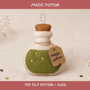 May include: A felt potion bottle ornament in cream and olive green with a brown cork top. The bottle features three small gold star embellishments and a brown paper tag tied with twine that has the text magic potion written in black ink.