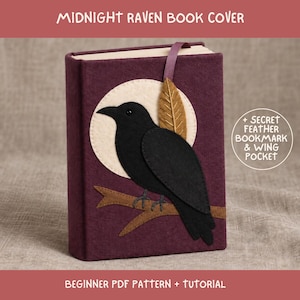 Puede incluir: Una funda de libro de fieltro morado oscuro con una aplicación de cuervo negro posado en una rama marrón sobre una luna color crema. Incluye un marcapáginas de cinta morada, una pluma marrón y el texto MIDNIGHT RAVEN BOOK COVER.