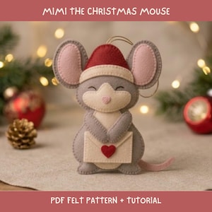 May include: A felt mouse ornament named Mimi the Christmas Mouse, featuring a grey body, pink inner ears, and a red Santa hat with a white trim. The mouse holds a cream-coloured envelope with a small red heart, and includes a gold hanging loop.