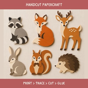 Peut inclure: Ensemble de papercraft découpé à la main représentant six animaux des bois : un raton laveur gris, un renard orange, un cerf brun à taches blanches, un lapin gris, un écureuil brun à grande queue et un hérisson brun. Texte : HANDCUT PAPERCRAFT et PRINT > TRACE > CUT > GLUE.