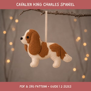 May include: A felt Cavalier King Charles Spaniel ornament in cream and brown, hanging from a light ribbon. The text CAVALIER KING CHARLES SPANIEL appears at the top, with PDF & SVG PATTERN + GUIDE | 2 SIZES printed at the bottom of the image.